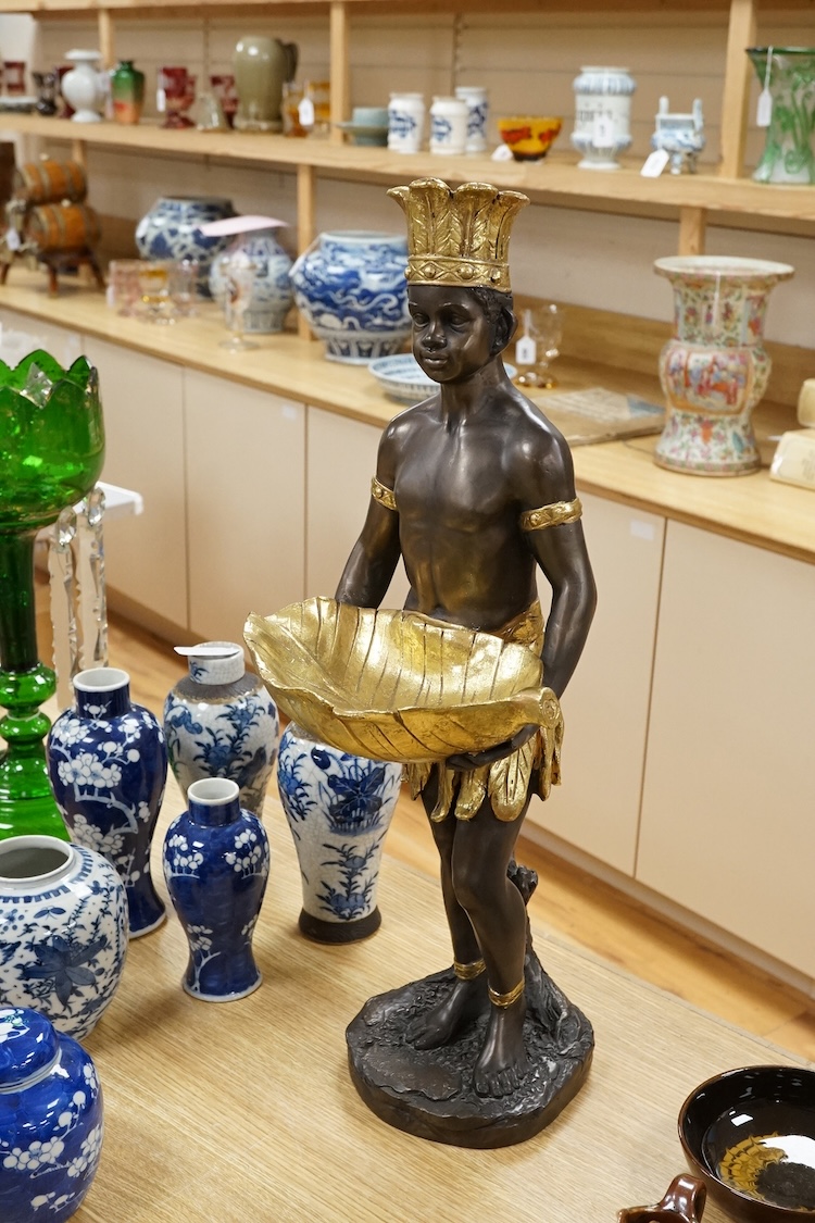 A gilded resin model of an Nubian boy holding a shell and wearing a crown, 65cm high.
